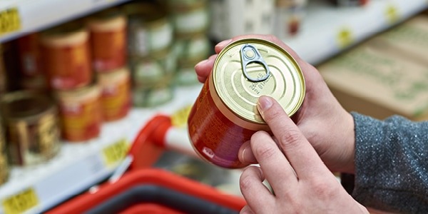 A person looking at date labels on canned good